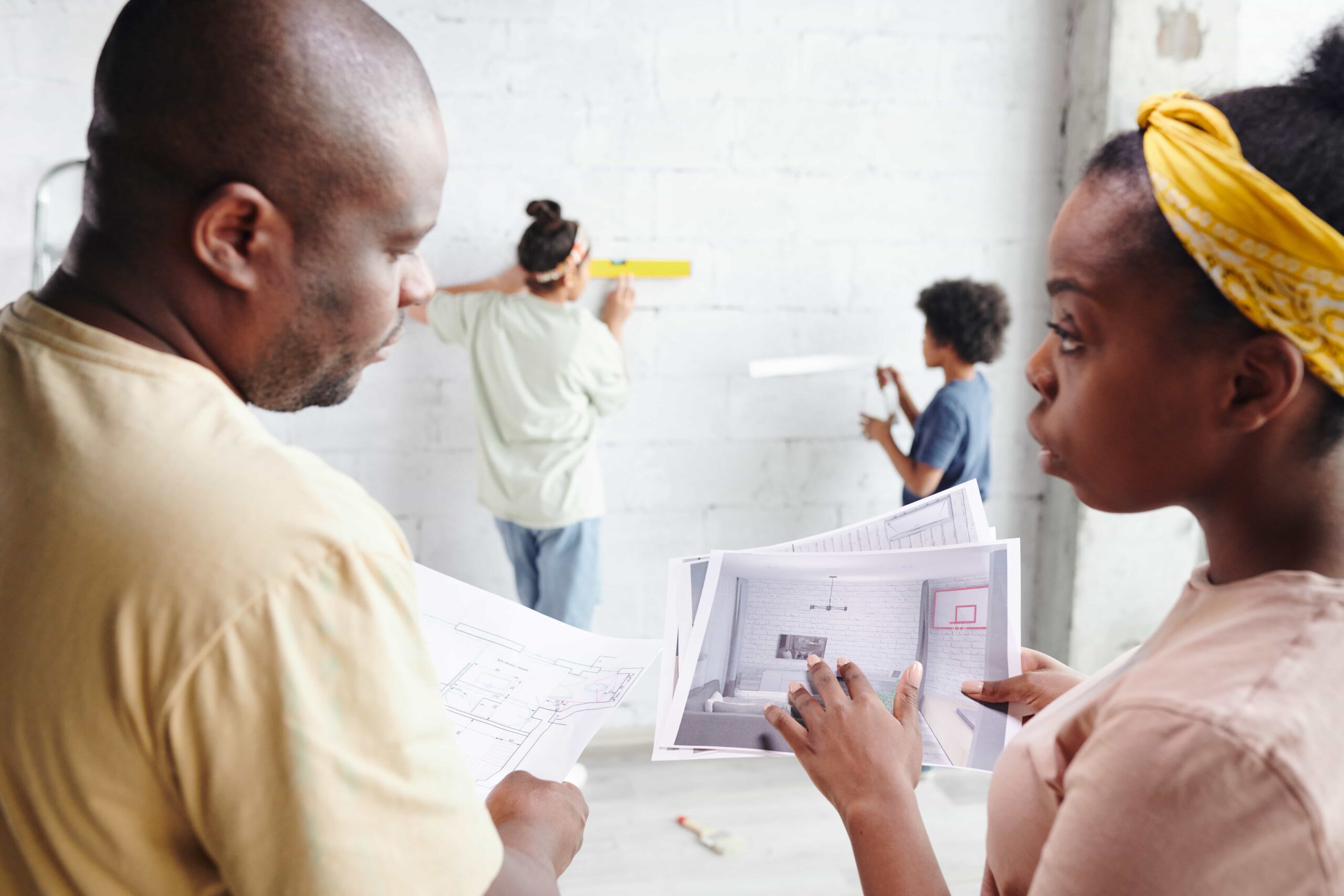 young-husband-wife-casualwear-discussing-papers-with-draft-interior-living-room-while-their-son-daughter-helping-them-min